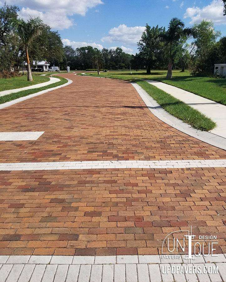 Paved walkway featuring colorful bricks and landscaped greenery in a sunny setting.