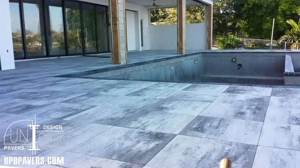 Modern outdoor patio with gray pavers and a pool area, enhancing contemporary landscaping design.
