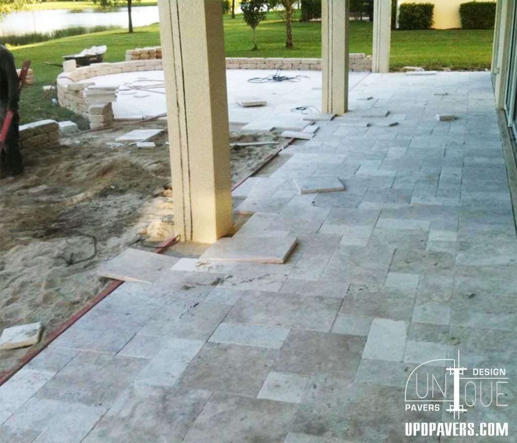Outdoor patio installation featuring tiled flooring and landscaping progress.