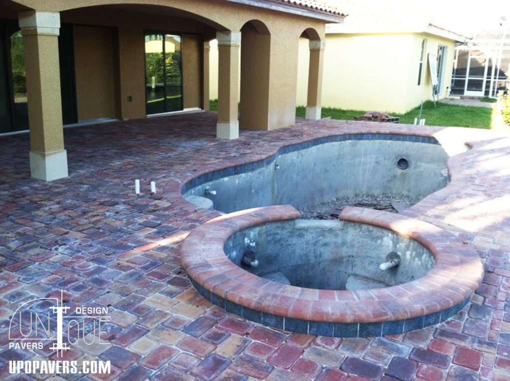 Outdoor patio featuring a stone paver deck and an unfinished pool and spa installation.