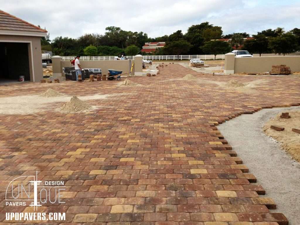 Paver installation in a residential area with workers and equipment on-site.