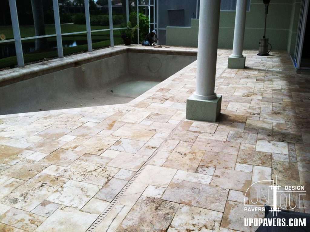 Paver stones around empty swimming pool in a sunny outdoor setting.