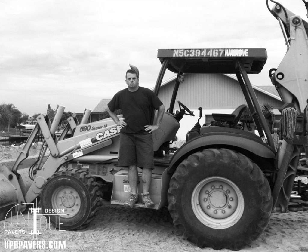Man standing on a tractor at a construction site, showcasing heavy machinery use.