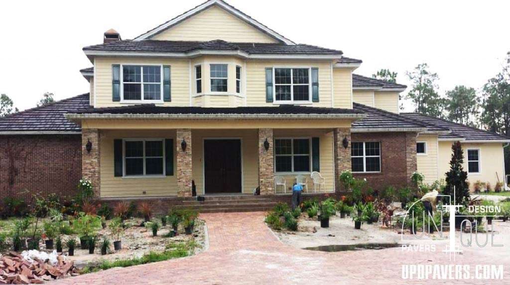 Modern two-story house with a stone and brick facade, surrounded by landscaping and paving.