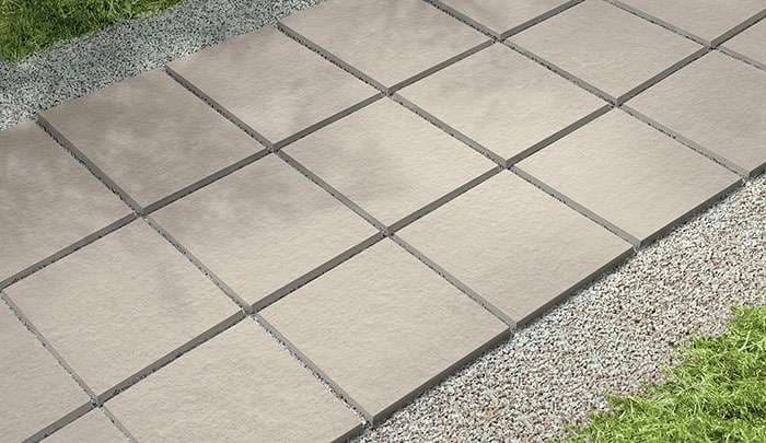 Paved stone walkway with rectangular slabs amidst grass and gravel. Ideal for landscaping.