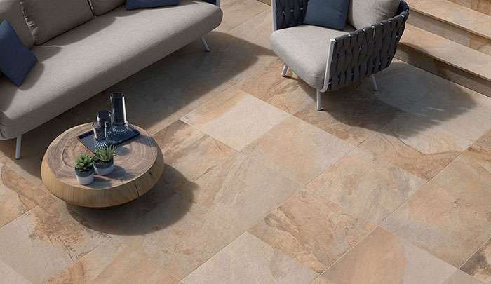 Modern outdoor patio featuring stylish furniture and textured stone tiles.