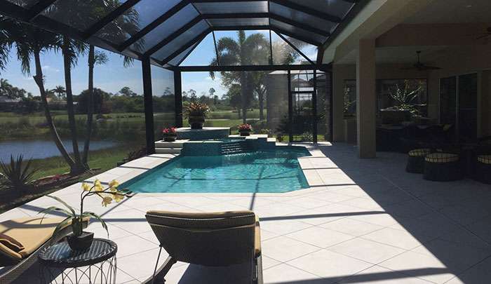 Modern screened patio with pool, lounge chairs, and a serene lake view in a sunny setting.