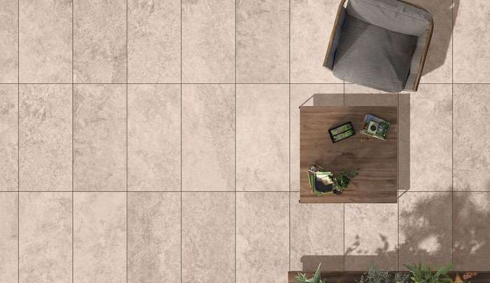 Modern interior with light tile flooring, a gray armchair, wooden table, and potted plants.