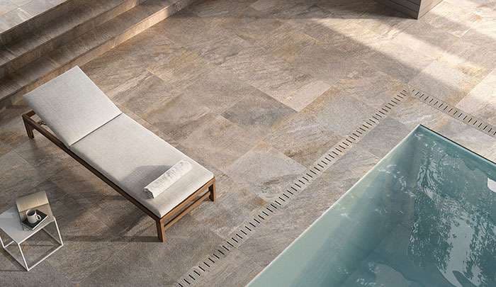 Luxurious poolside lounge area with stone tiles, a sunbed, and sleek water features.