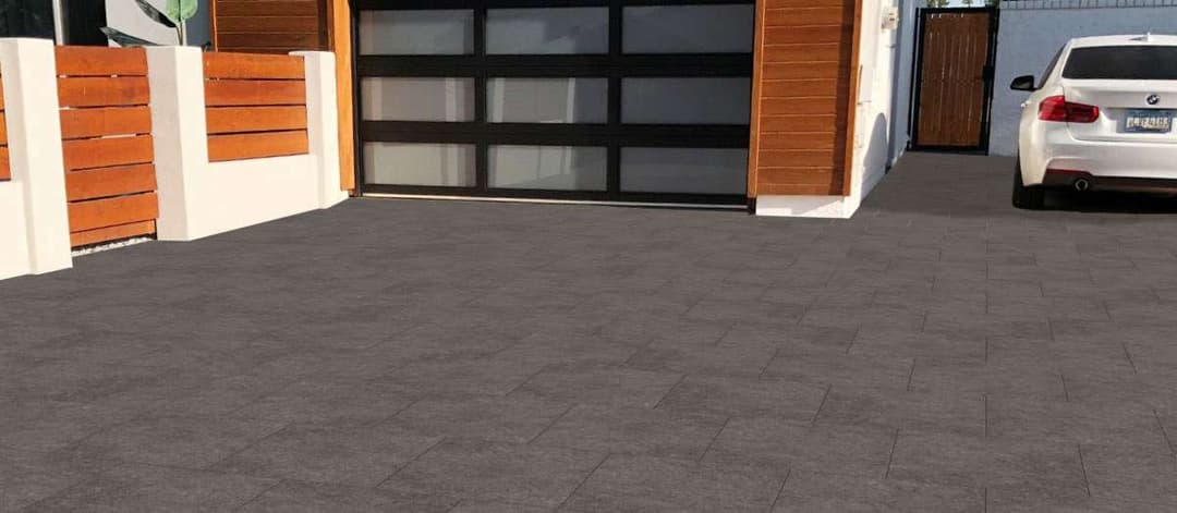 Modern driveway with dark pavers and a sleek white car beside a stylish garage.