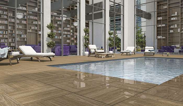 Modern indoor pool area with lounge chairs, wood decking, and large windows for natural light.