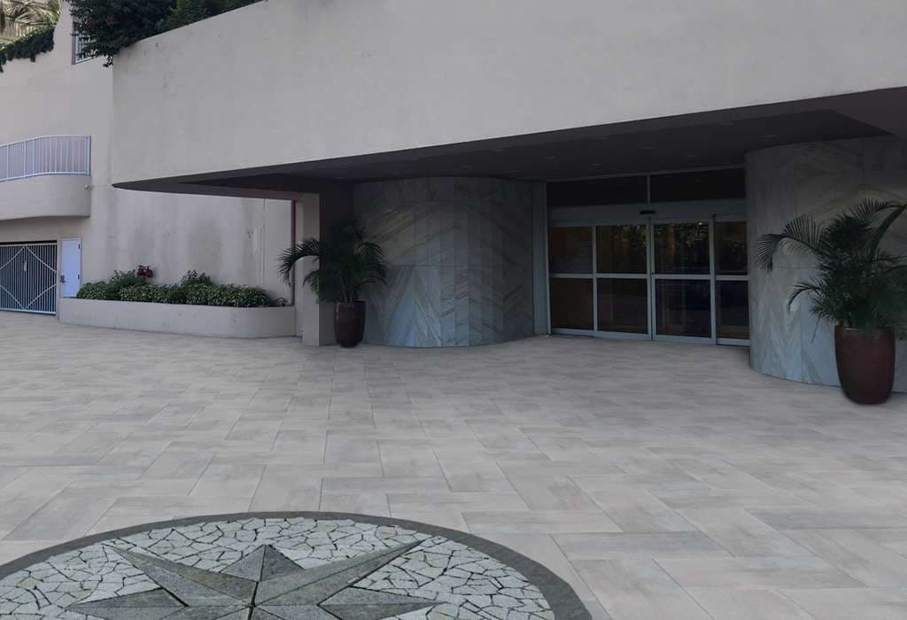 Modern building entrance with glass doors and decorative stone plaza design.