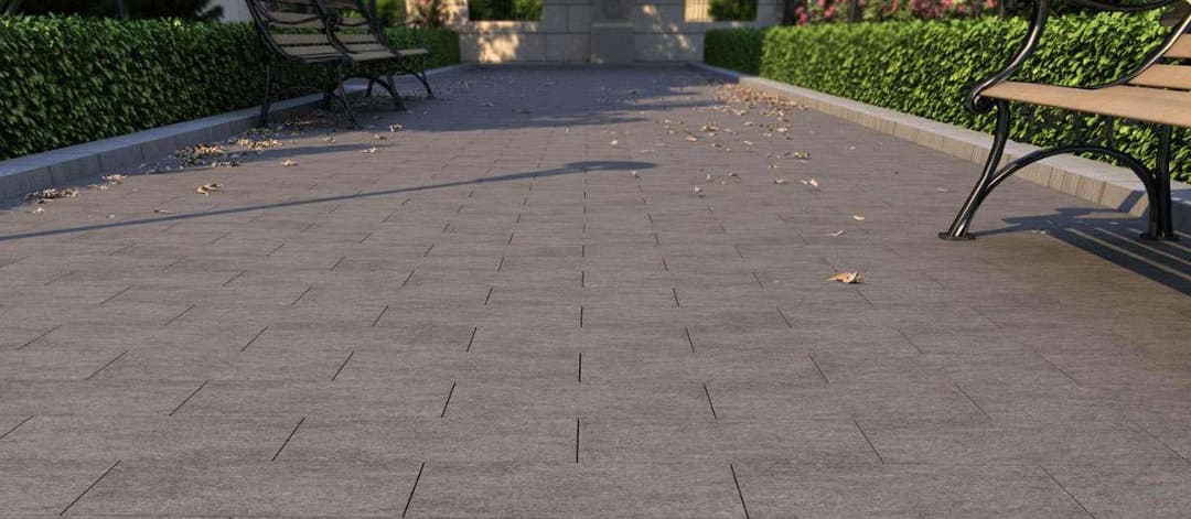 Paved walkway with benches and landscaped greenery in a tranquil outdoor setting.