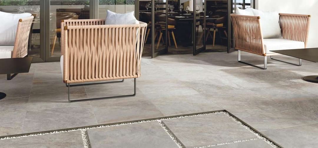 Modern outdoor patio with sleek gray tiles, stylish furniture, and elegant dining setup.