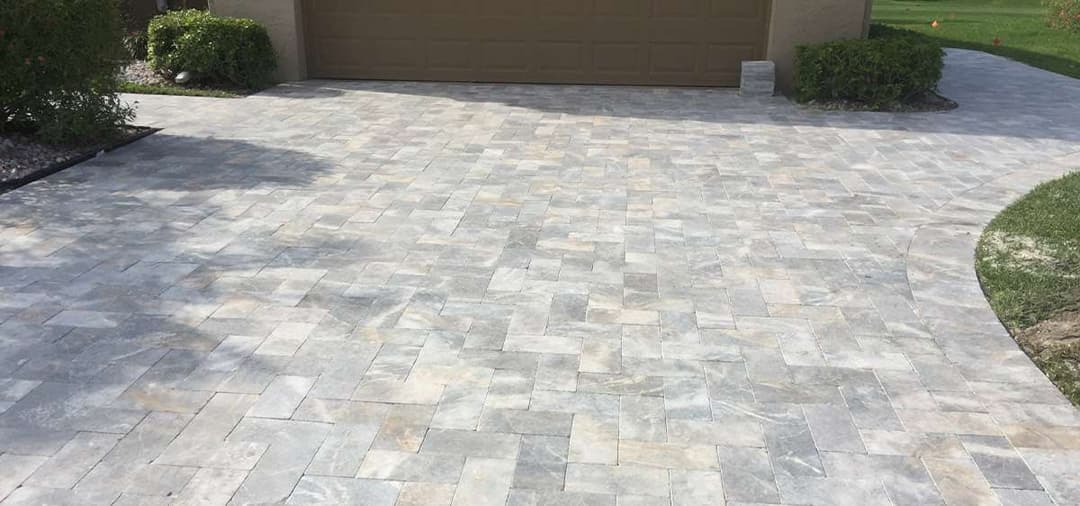 Stylish gray paver driveway with a modern garage door, enhancing curb appeal.