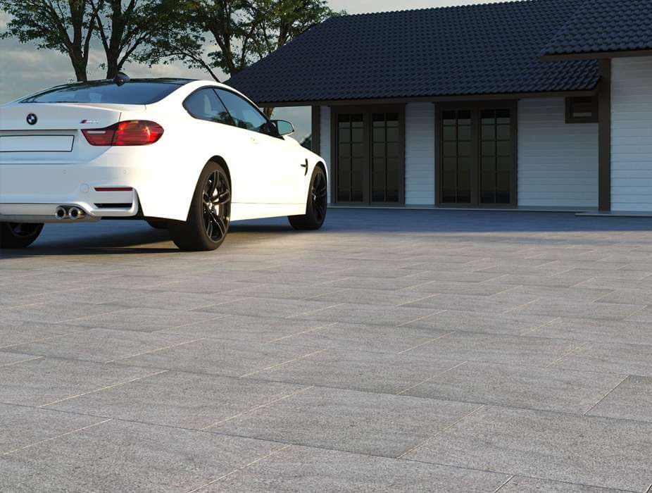 White BMW parked on gray tiles in front of a modern house with a dark roof.