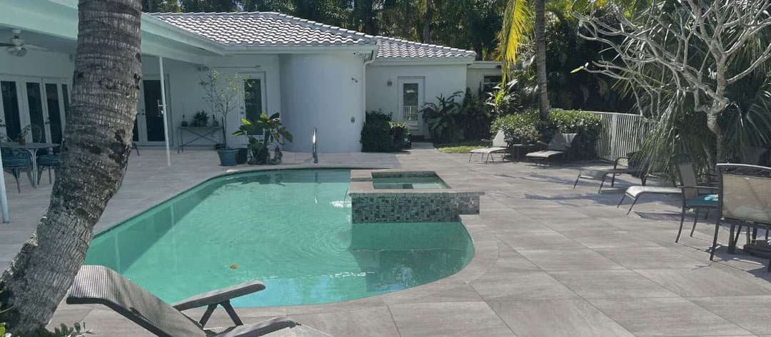 Luxury backyard with a pool, spa, and stylish seating in a tropical setting.