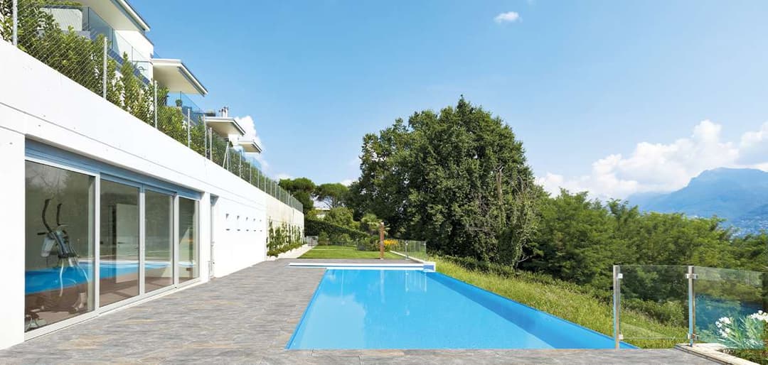 Modern villa with swimming pool and scenic view of lush greenery and mountains.