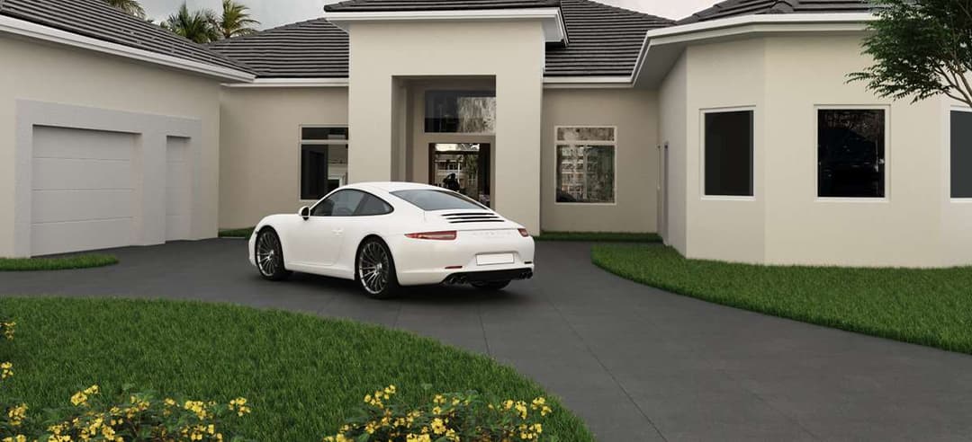 White sports car parked in driveway of modern house with green landscaping.
