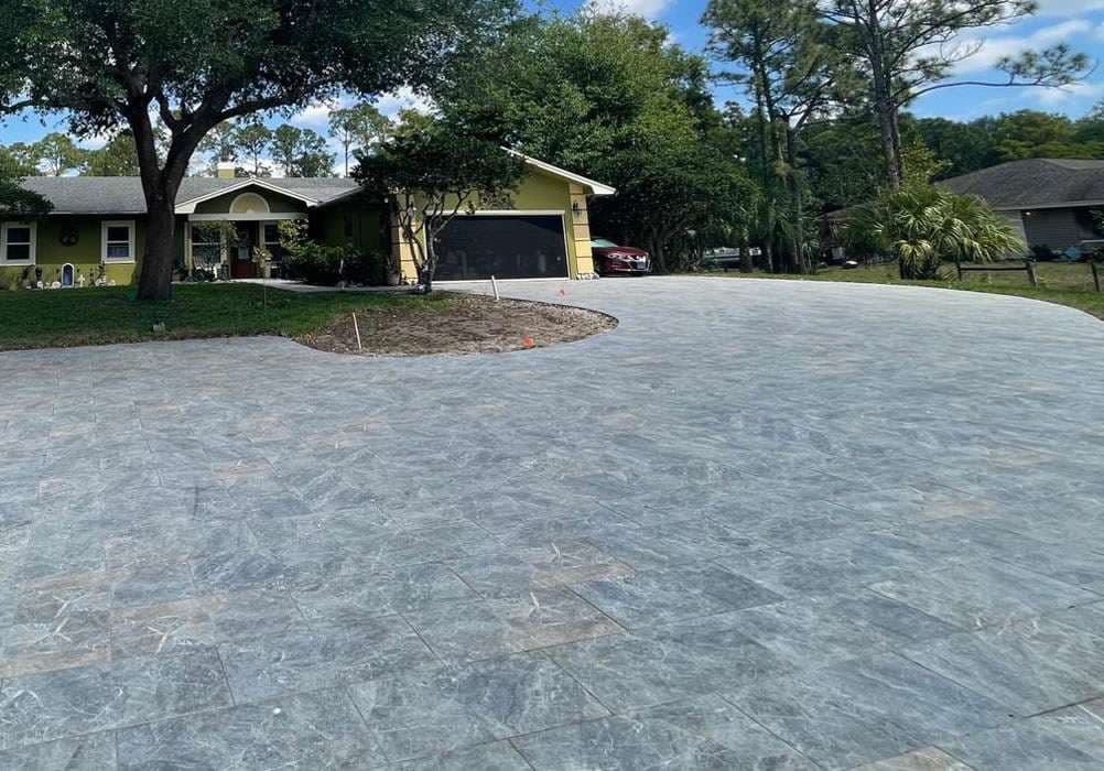 Stylish stamped concrete driveway with a landscaped yard and modern home in the background.