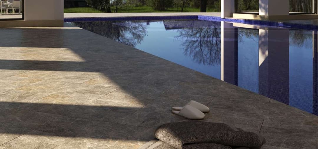 Luxury poolside with elegant tiles, towels, and slippers, surrounded by greenery.