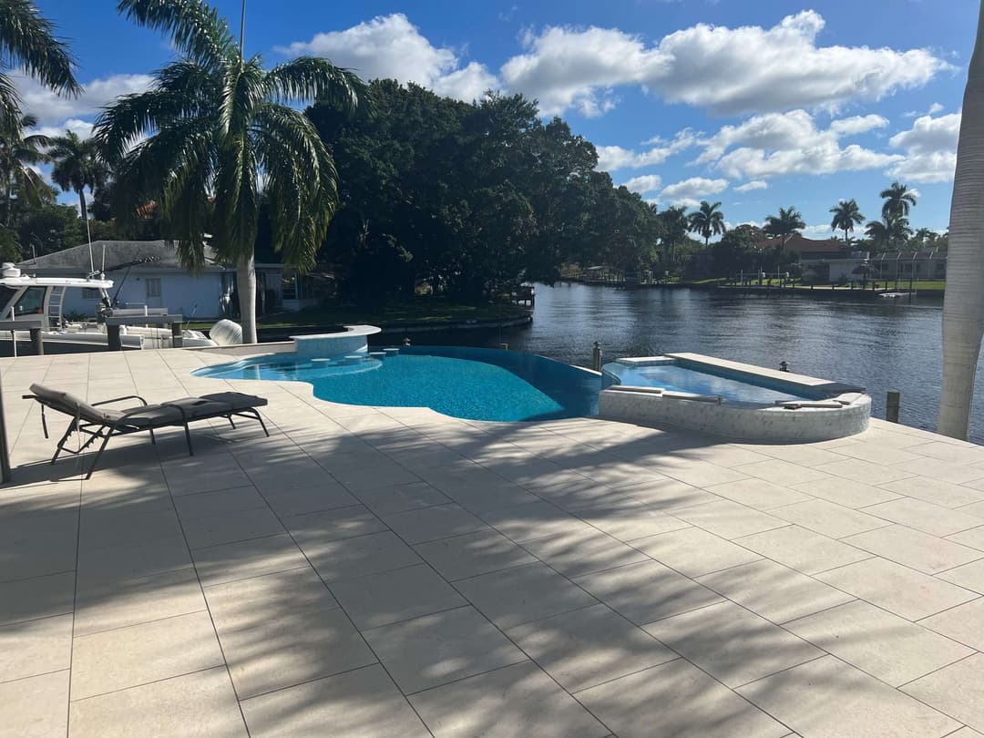 Luxurious pool area with loungers, palm trees, and serene water views.