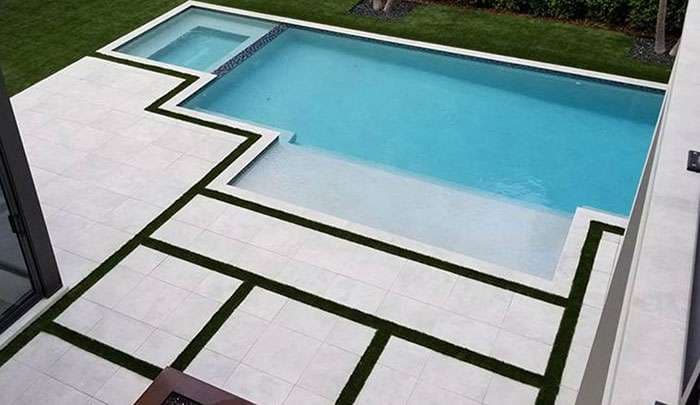 Modern backyard with geometric pool design and landscaped grass areas. Ideal for relaxation.