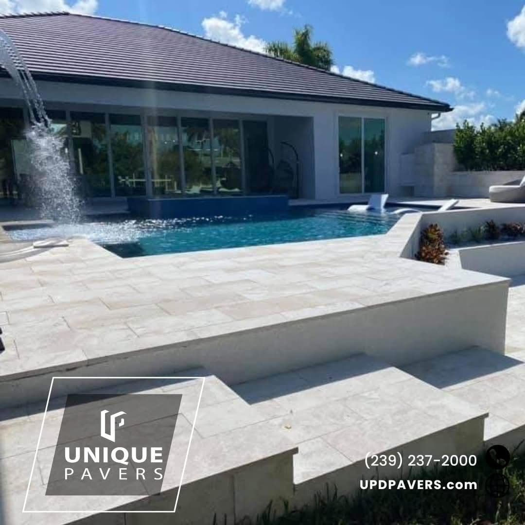 Modern outdoor pool surrounded by elegant pavers and lush landscaping, showcasing luxury design.